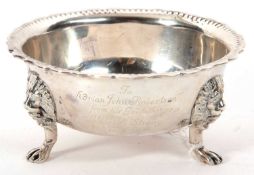 A George V silver bowl of round form having an applied wavey and beaded rim, supported on three lion