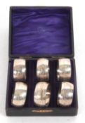 Cased set of six matching silver serviette rings, chased and engraved with leaves around a vacant