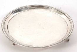 A George III silver card salver having beaded rim, the centre engraved with an armorial, supported