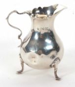 A Victorian cream jug of typical form having card cut rim and scroll handle, supported on three hoof