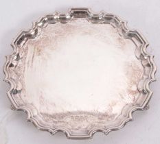 An Elizabeth II silver card salver of circular form having a pie crust border and supported on three