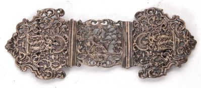 An antique white metal pierced cast two part hinged buckle with figural and scroll design (