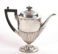 An Edwardian silver coffee pot of oval form having a part fluted body on an oval spreading foot,