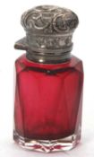An antique small cranberry glass and silver scent bottle, the body a faceted design with embossed