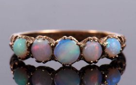 A five stone opal ring, the round graduated opal cabochons claw mounted to shaped shoulders and