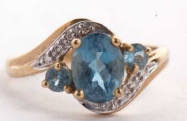 A 9ct topaz and diamond crossover style ring, the oval topaz set to either side with a smaller round