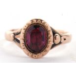 An 18ct garnet ring, the oval garnet in rubover mount with moulded decoration surround and closed