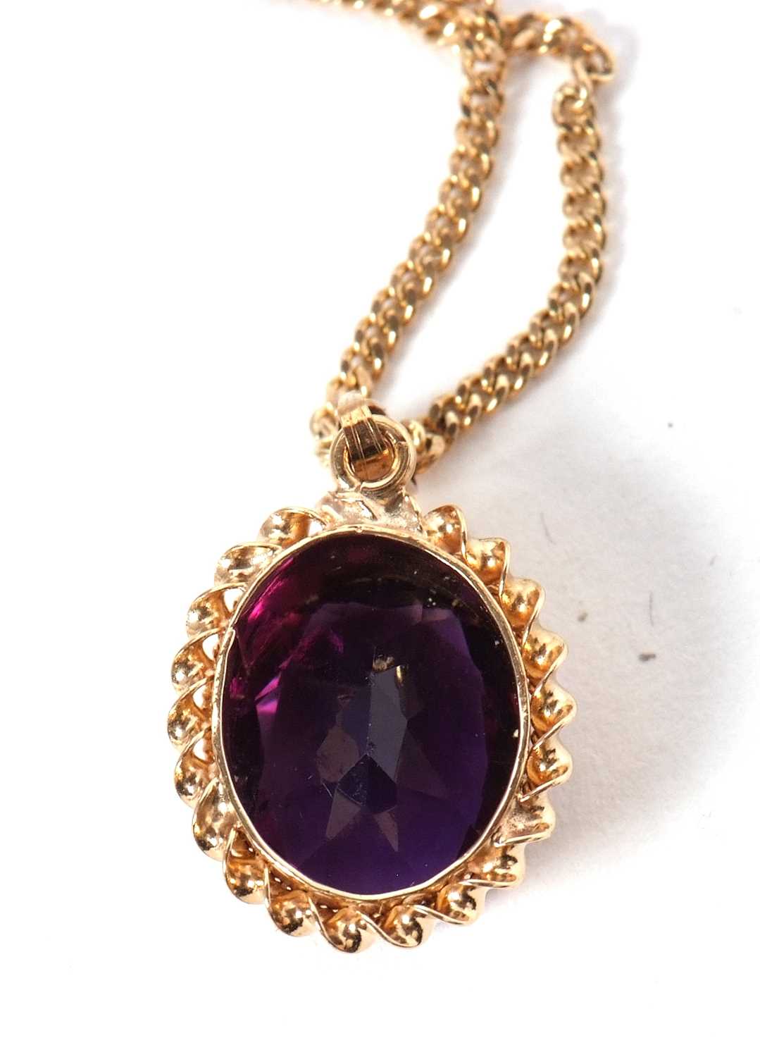 A 9ct amethyst pendant, the oval amethyst in deep collet mount wtih twisted border, bale stamped