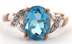 A 9ct topaz and diamond ring, the oval mixed cut topaz claw mounted within a crossover style mount