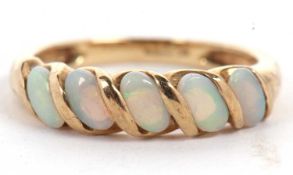 A 9ct opal ring, the five oval opal cabochons set at a 45° angle with a twist of gold separting