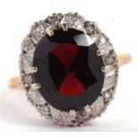 A 9ct garnet and diamond ring, the oval faceted garnet surrounded by small round illusion set