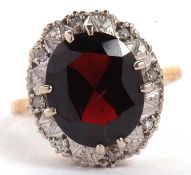 A 9ct garnet and diamond ring, the oval faceted garnet surrounded by small round illusion set