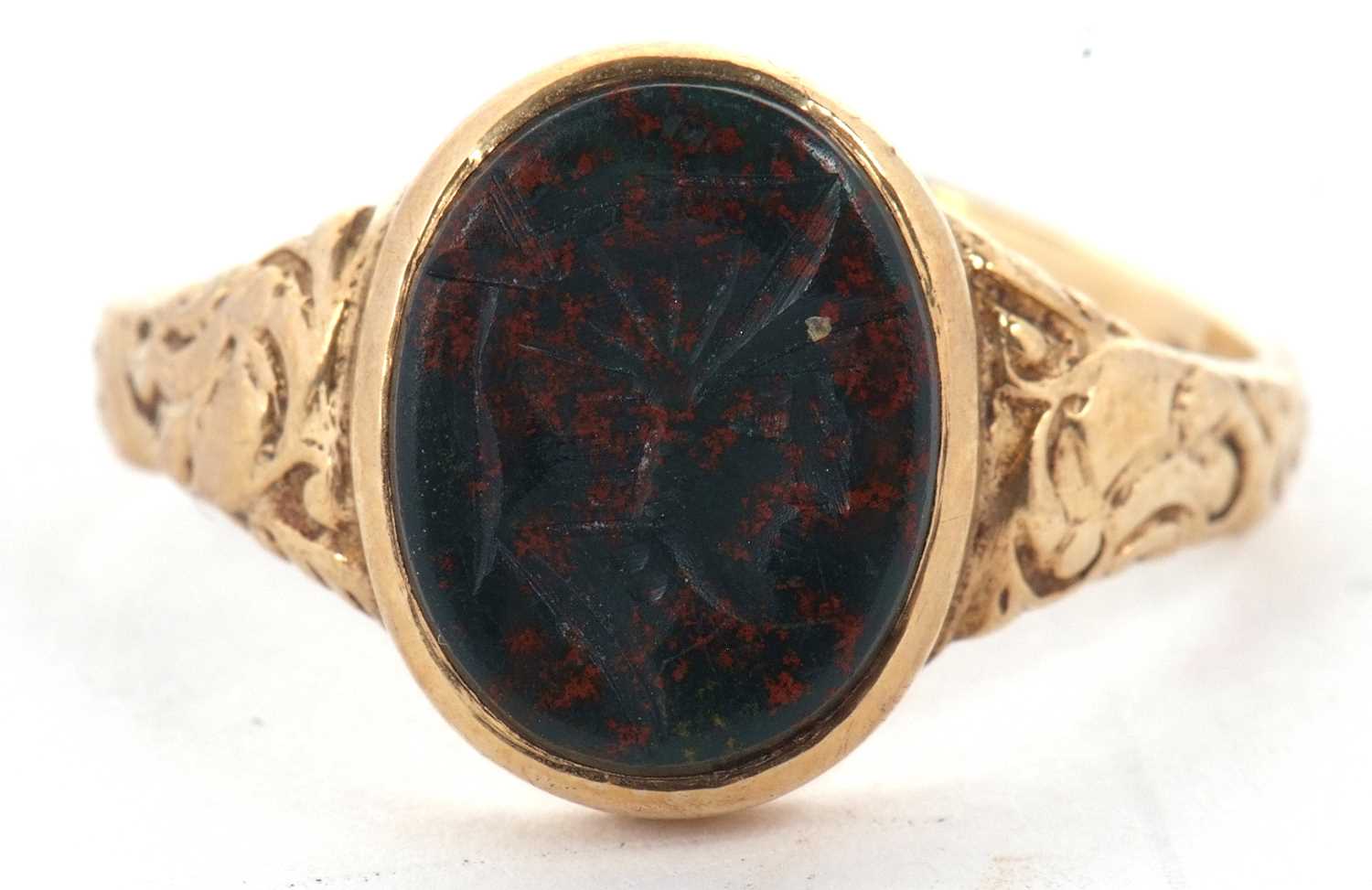 A 9ct bloodstone intaglio ring, the oval bloodstone intaglio, in rubover mount with repousse tapered
