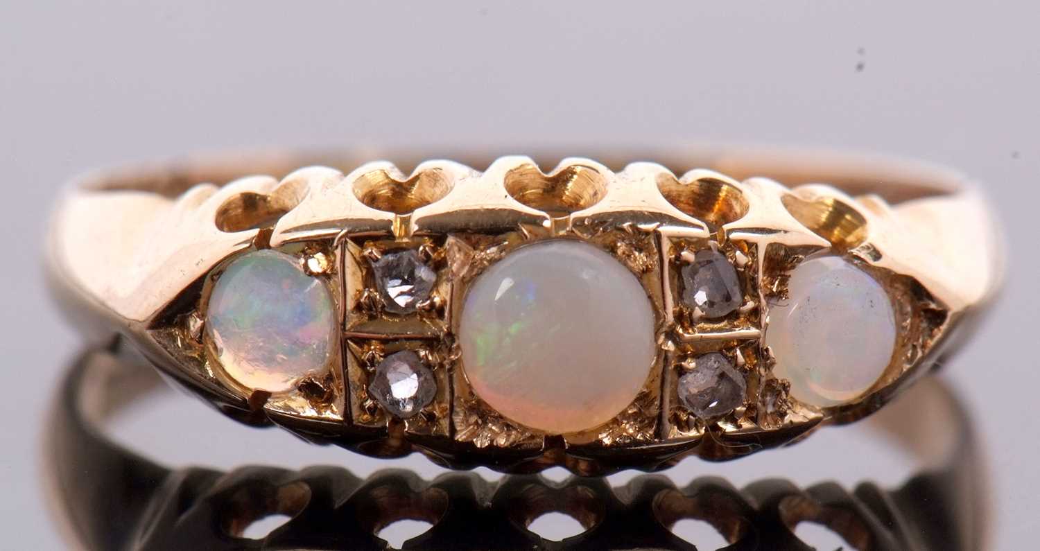 An 18ct opal and diamond ring, the three round opal cabochons interspaced with diamond highlights,