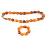 An amber bead necklace, the oval beads with small glass spacers and gilt metal barrel clasp, 49cm
