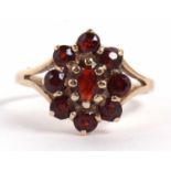 A 9ct garnet cluster ring, set with oval garnets, with split shoulders and plain band, hallmarked
