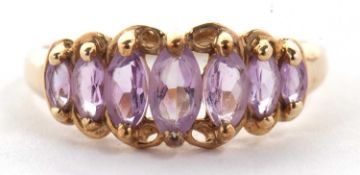 A 9ct gemset ring, the seven graduated marquise pale lavender-pink stones, claw set to plain band
