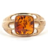 A 9ct amber ring, the square amber cabochon, collet mounted with pierced scalloped shoulders and