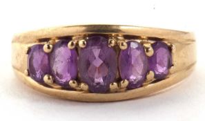 A 9ct amethyst ring, the five graduated oval amethyst, claw mounted within a tapering channel, 8.3mm