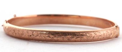 A 9ct rose gold hinged bangle, the upper half with stylised ivy leaf engraved decoration, lower half