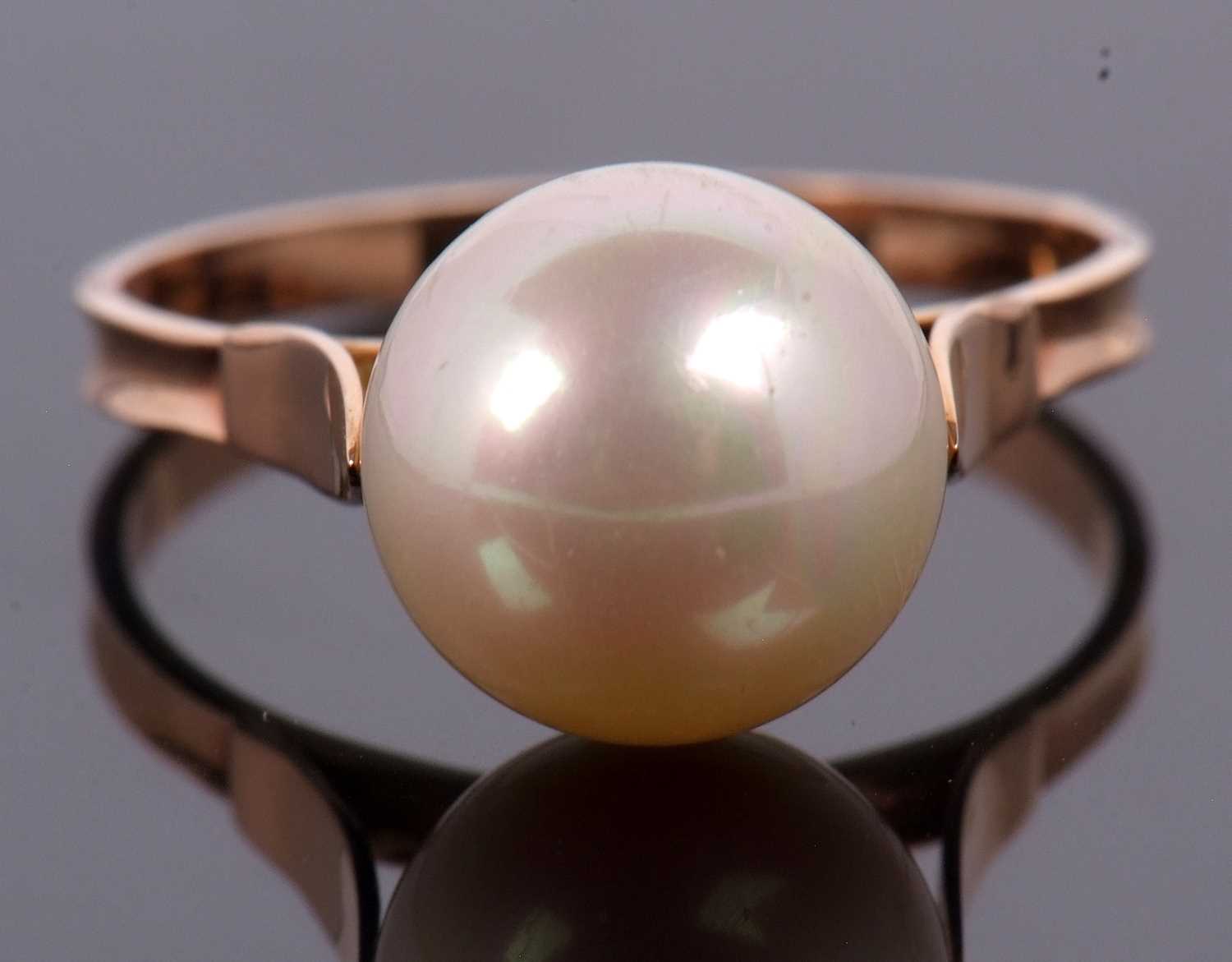 A cultured pearl ring, the cultured pearl approx. 1cm diameter, with cup and two claw mount, to a