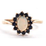 A 9ct sapphire and opal cluster ring, the central oval opal cabochon surrounded by small round