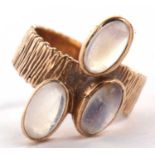 A 9ct three stone moonstone ring, the three oval moonstone cabochons, collet mounted to a textured