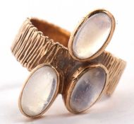 A 9ct three stone moonstone ring, the three oval moonstone cabochons, collet mounted to a textured