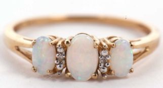 A 9ct opal and diamond ring, the three slightly graduated oval opal cabochons interspaced with a