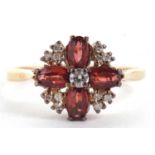 A 9ct garnet and diamond ring, the central round brilliant cut diamond surounded by four oval