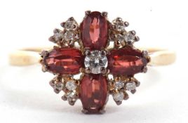 A 9ct garnet and diamond ring, the central round brilliant cut diamond surounded by four oval