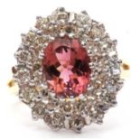An 18ct pink tourmaline and diamond cluster ring, the oval pink tourmaline, claw mounted and