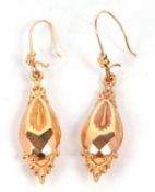 A pair of gold pendant earrings, the teardrop shape drops with repousse moulded finials and