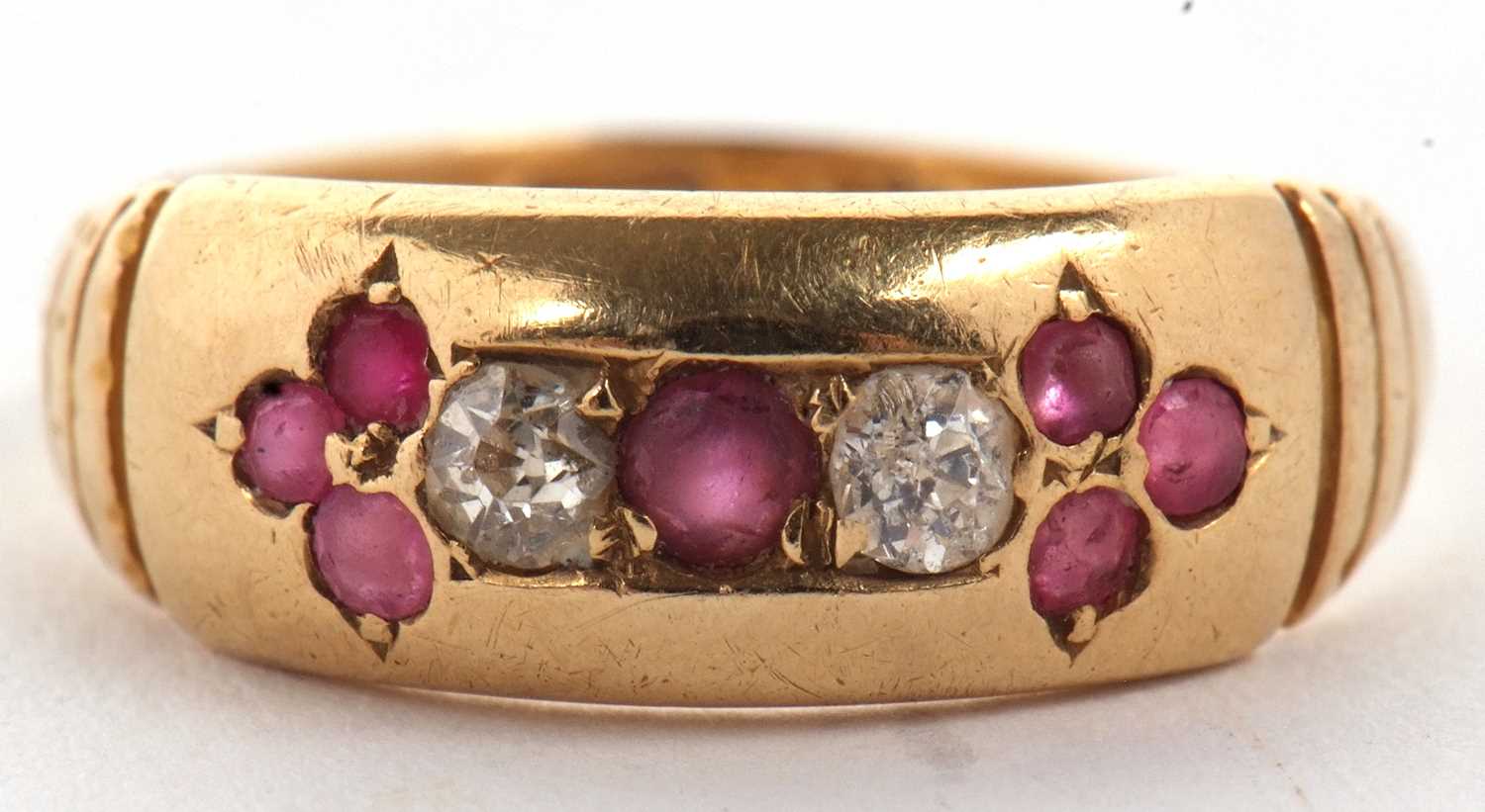 An 18ct ruby and diamond ring, the central round ruby set to either side with a round diamond and