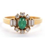 An 18ct emerald and diamond ring, the central oval emerald set with three small round diamonds above