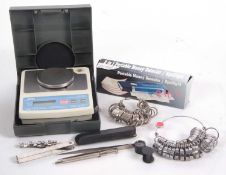 A group of jewellers equipment to include a set of weighing scales, two sets of finger sizers, a