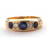 An Edwardian 18ct sapphire and diamond ring, the three graduated round sapphires interspaced with