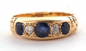 An Edwardian 18ct sapphire and diamond ring, the three graduated round sapphires interspaced with
