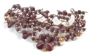 An adapted garnet brooch, the curled floral frond set with mixed cut garnets with closed backs,