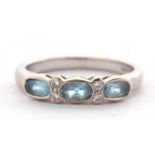 An 18ct aquamarine and diamond ring, the three oval aquamarines seperated by two small round