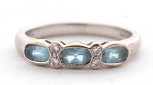 An 18ct aquamarine and diamond ring, the three oval aquamarines seperated by two small round