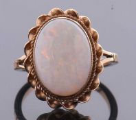 A 9ct opal ring, the oval opal cabochon, approx. 14 x 10mm, collet mounted with twisted border and