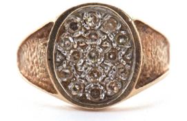 A 9ct diamond ring, with a pave diamond set oval disc, 14mm wide, with concave textured tapering