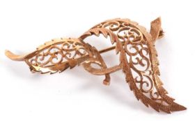 A 9ct leaf brooch, the two curving leaves with outer textured edges and inner scrolled wirework,