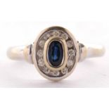 An 18ct sapphire and diamond ring, the collet mounted oval sapphire surrounded by a ring of