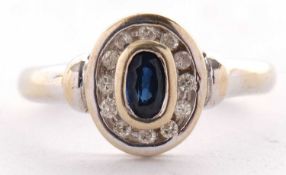 An 18ct sapphire and diamond ring, the collet mounted oval sapphire surrounded by a ring of