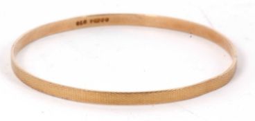 A 9ct upper arm gold bangle, the 4.5mm wide bangle with engine turned decoration, hallmarked