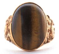 A 9ct tigers eye ring, the oval tigers eye cabochon, collet mounted to tapered textured shoulders