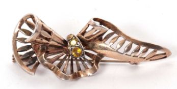 A mid 20th century silver gilt and yellow hardstone brooch, the pierced, curled ribbon, tapering
