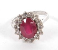 A silver ruby and white topaz ring, the oval ruby surrounded by small round topaz, all set in silver